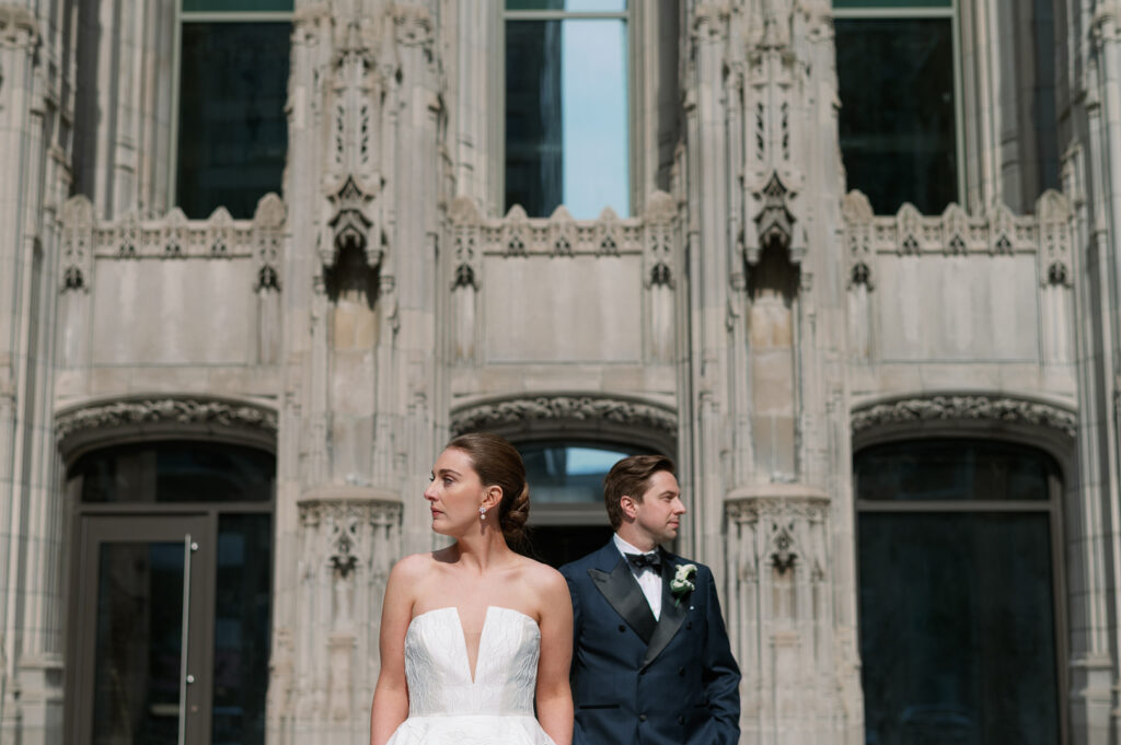 couple posing for wedding photos outside of the tribune tower in chicago illinois